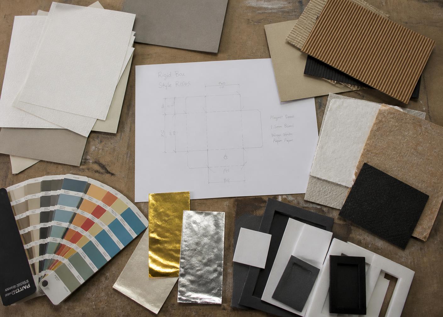 Paperboard, corrugated and foil material samples with a dieline sketch